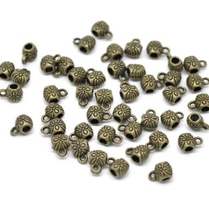 May include: A group of antique gold-toned metal bead caps with a floral design. Each cap has a small loop for attaching to jewelry.