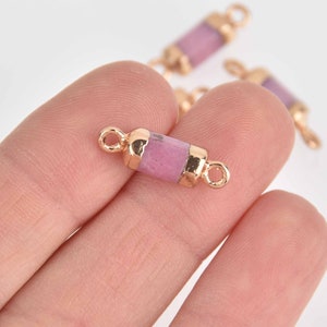 May include: Gold-tone connector with a pink stone insert. The connector has two loops on either end.