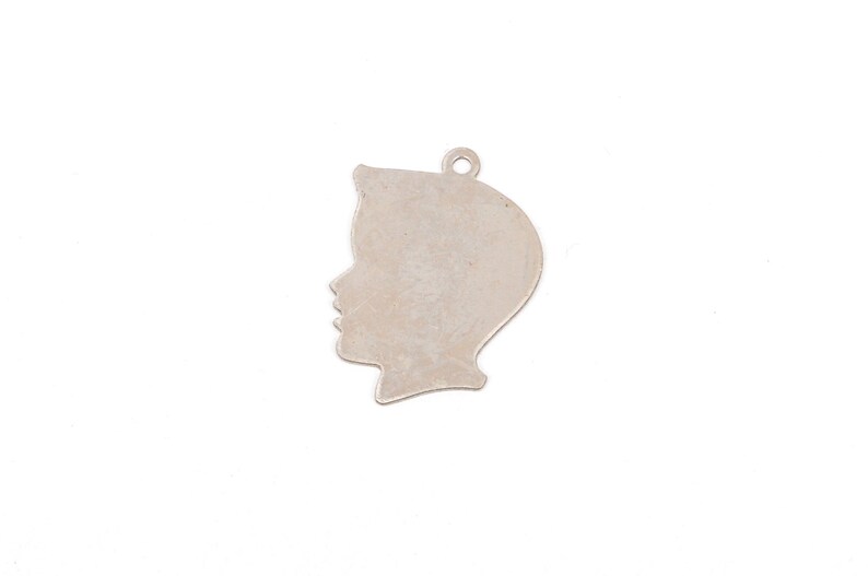 May include: Silver charm in the shape of a person's profile. The charm is a silhouette of a person's head and shoulders.