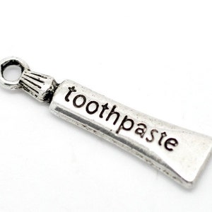 May include: Silver charm shaped like a tube of toothpaste with the word "toothpaste" engraved on it.