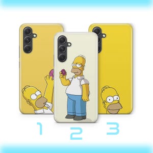 May include: Three smartphone cases featuring Homer Simpson. The left case is yellow with Homer reaching for a doughnut. The centre case is off-white with a full-body Homer holding a doughnut. The right case is yellow with Homer's head at the bottom.