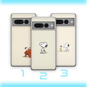 Puede incluir: Tres fundas para teléfono de color crema con diseños de Snoopy. Cada funda tiene una ilustración diferente de Snoopy en blanco y negro. Una muestra a Snoopy de pie, otra a Snoopy en su caseta y la tercera a Snoopy con una flor. Las fundas tienen un recorte para la cámara.
