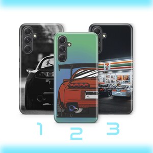 以下が含まれることがあります： 自動車デザインのスマートフォンケース3点。1つ目は白黒の車のリア、2つ目は緑のグラデーション背景にスポイラー付きの赤い車のイラスト、3つ目はセブンイレブンの店舗前に駐車された車の写真がプリントされています。