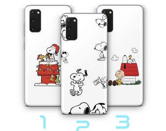 May include: Three white phone cases with Snoopy designs. One case shows Snoopy on a red doghouse with Charlie Brown, another has Snoopy with "Peace Love", and the third features Snoopy on a chimney with Christmas lights.
