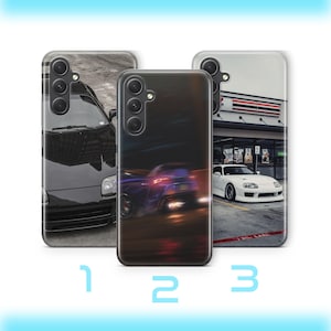 May include: Three smartphone cases featuring automotive designs. The first shows a black car, the second a motion-blurred purple car, and the third a white car parked in front of a building. Each case has a triple-lens camera cutout.