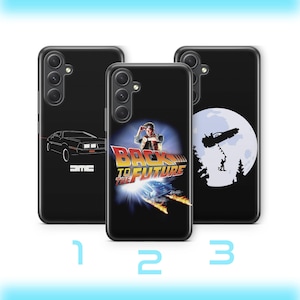 Könnte beinhalten: Drei schwarze Handyhüllen mit verschiedenen Designs. Eine zeigt eine DeLorean-Grafik, eine andere das "Zurück in die Zukunft"-Filmlogo und die dritte eine Silhouette eines fliegenden Autos und einer Person.