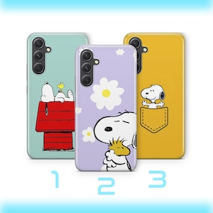 May include: Three phone cases with Snoopy designs. The first case is light blue with Snoopy on his doghouse. The second case is lavender with Snoopy and a daisy. The third case is yellow with Snoopy in a pocket.