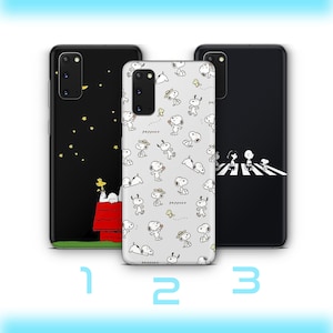 Puede incluir: Tres fundas de teléfono con diferentes diseños. Una funda negra presenta a Snoopy en su caseta con estrellas amarillas. Otra funda es blanca con Snoopy en varias poses. La tercera funda es negra con Snoopy y sus amigos cruzando una calle.
