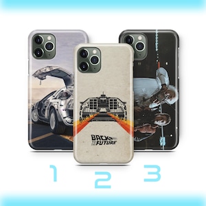 May include: Three phone cases with different designs. One case features a DeLorean car with its door open, another has a graphic of the DeLorean with the text "Back to the Future", and the third case shows a scene from the movie.