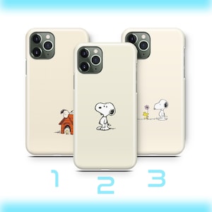 May include: Three cream-coloured phone cases featuring Snoopy designs. One case shows Snoopy by his doghouse, another has Snoopy standing, and the third depicts Snoopy with a flower. Numbers 1, 2, and 3 are printed below the cases.