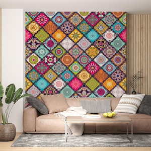 May include: A colorful wall mural featuring a patchwork design with geometric patterns in various colors, including pink, orange, blue, and green. The mural is above a brown leather sofa with pillows and a coffee table. A potted plant is on the left.