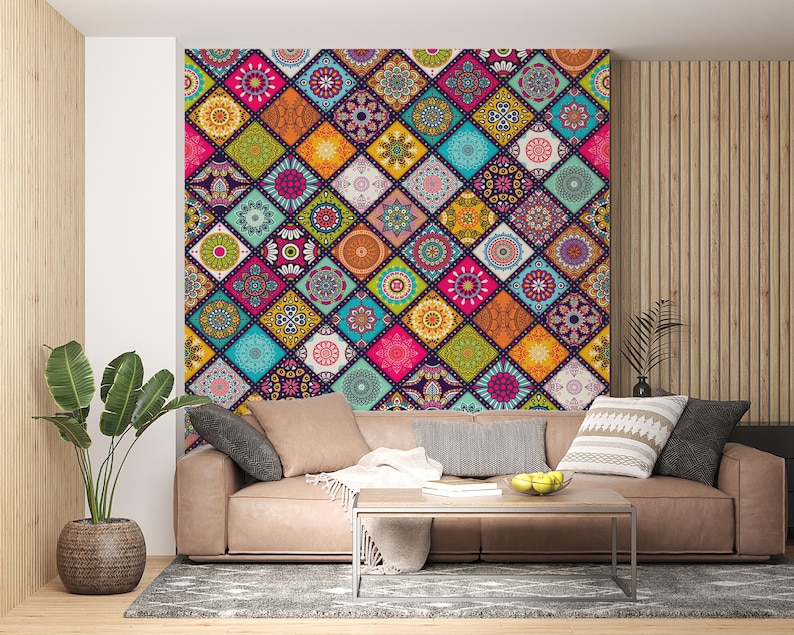 May include: A colorful wall mural featuring a patchwork design with geometric patterns in various colors, including pink, orange, blue, and green. The mural is above a brown leather sofa with pillows and a coffee table. A potted plant is on the left.