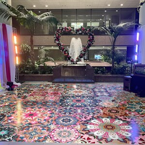 May include: An event space with a heart-shaped floral arrangement around a fountain. The floor is covered in colourful, patterned tiles. Palm trees and lighting fixtures are also visible.