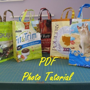 May include: Five colorful reusable shopping bags made from recycled plastic food packaging. The bags are all different colors and have different designs, including a cat, a dog, and a chicken. The bags are all lined up on a green cutting mat. The text "PDF Photo Tutorial" is written in yellow on the mat.