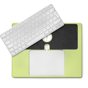 May include: A light green laptop case with a white keyboard and a white trackpad. The keyboard is positioned above the case, and the trackpad is located at the bottom. The case has a black area in the centre.