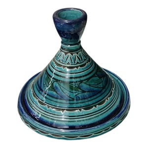 May include: A teal and blue ceramic tagine pot with a conical lid and a round base. The lid features a decorative leaf pattern and geometric designs. The tagine is a traditional Moroccan cooking vessel.