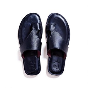 May include: A pair of navy blue leather sandals with a thong-style design. The sandals have a stitched border and a dark red interior. The image is a top-down view of the footwear.