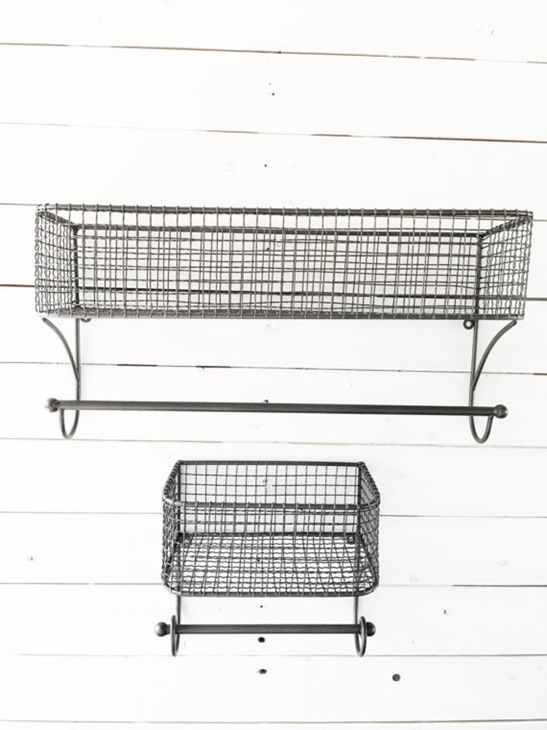 May include: Two black metal wire shelves with towel bars. The top shelf is larger than the bottom shelf. Both shelves have a simple, industrial design.