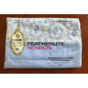 Puede incluir: Paquete sellado de una sábana plana Featherlite sin plancha de la familia real Cannon. La sábana tiene un estampado floral azul claro sobre un fondo blanco. El paquete está etiquetado para un colchón de tamaño completo, 137 x 193 cm.