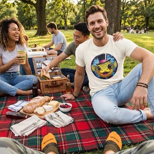 May include: A group of people enjoying a picnic on a red and green plaid blanket. The picnic includes bread, cheese, and berries. One person wears a white t-shirt with a colorful fish graphic. The scene is set in a park with trees.