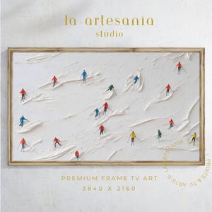 以下が含まれることがあります： テクスチャ加工された白い背景に、カラフルな衣装を着たミニチュアのスキーヤーが描かれた額入りのアートプリント。「la artesanía studio」と「PREMIUM FRAME TV ART 3840 X 2160」の文字が含まれています。フレームは明るい茶色です。