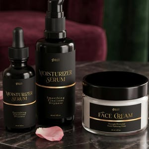 Peut inclure: Deux flacons noirs de sérum hydratant avec compte-gouttes et pompe, et un pot transparent de crème pour le visage avec un couvercle noir. Chaque contenant présente des étiquettes noires avec du texte doré, incluant la marque et le volume en ml.