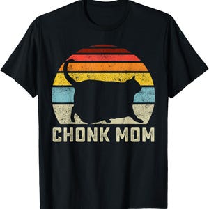 May include: Black t-shirt featuring a silhouette of a cat in front of a retro sunset design with orange, yellow, and blue stripes. The text "CHONK MOM" is printed below the cat.