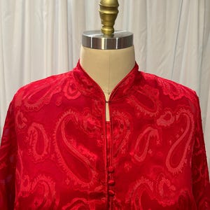 May include: A red paisley patterned button-up shirt with a mandarin collar.