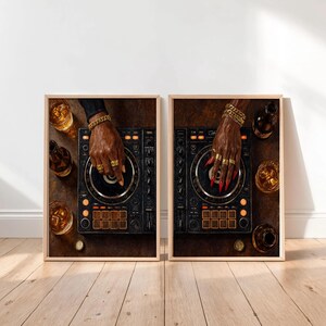 May include: Two framed wall art prints depicting a black DJ controller with orange buttons and knobs. One print shows a hand with gold rings and a bracelet, the other shows a hand with long red nails, gold rings, and a gold bracelet, both with glasses of amber liquid.