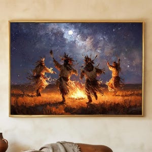 May include: A framed painting depicts Native American figures dancing around a fire under a starry night sky. The artwork features warm tones of orange and yellow from the fire, contrasting with the cool blues and purples of the night. The figures are in motion, suggesting a ceremonial dance.