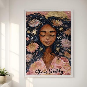 May include: A framed art print featuring a woman with closed eyes, adorned with flowers and gold accents in her hair. The artwork has a pink and gold background, and the text "She is Worthy" is at the bottom. The painting is displayed on a white wall.