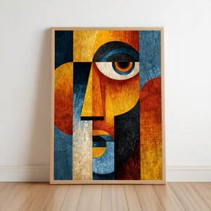 May include: Abstract art print featuring a stylized face composed of geometric shapes. The artwork uses a palette of warm colors, including gold, orange, and red, contrasted with cool blues and blacks. The framed print is displayed on a wall.