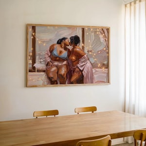May include: A rectangular framed oil painting depicting two individuals kissing near a window. One individual wears a light blue bra and light-colored shorts, while the other wears a light pink robe. Warm string lights are draped across the scene.