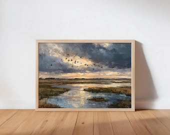 May include: A framed landscape painting depicts a marsh scene under a dramatic sky. Dark clouds contrast with the golden light of the setting sun. Silhouetted birds fly across the sky, and the painting is set in a light wood frame.