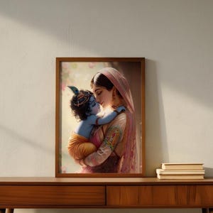 A framed painting of a woman holding a child is displayed on a wooden table against a white wall.