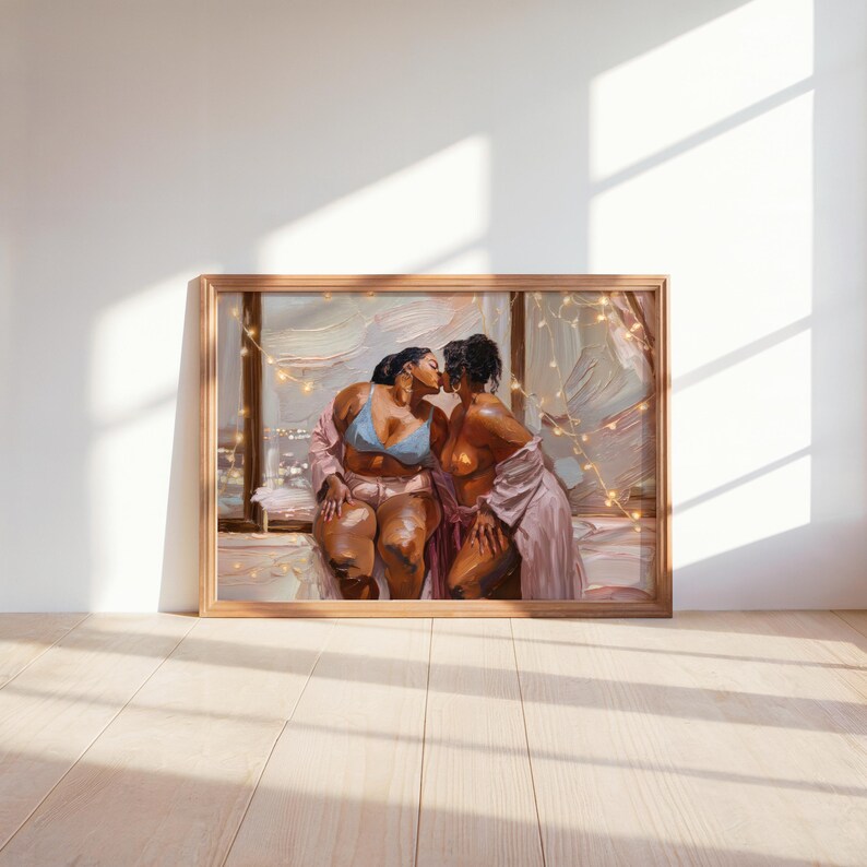 May include: A framed oil painting print depicting two figures kissing in front of a window at night. One figure wears a light blue bra and pink shorts, while the other wears a pink robe. The scene is illuminated by warm string lights.