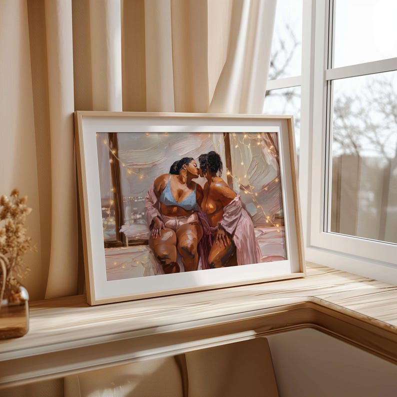 May include: A framed art print depicting two individuals kissing near a window at night. One individual wears a light blue bra and pink shorts, while the other wears a pink robe. The scene is illuminated by warm string lights against a dark background.