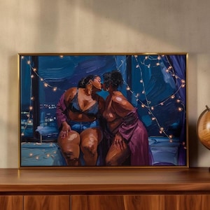 a painting of two women sitting together, with one woman appearing to kiss the other. The painting is framed and displayed on a wooden shelf or cabinet.