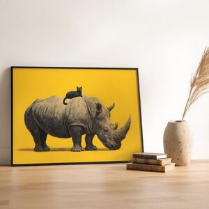 May include: A framed rectangular wall art print featuring a detailed illustration of a large gray rhinoceros standing in profile against a solid bright yellow background, with a small black cat resting on the back of the rhinoceros.