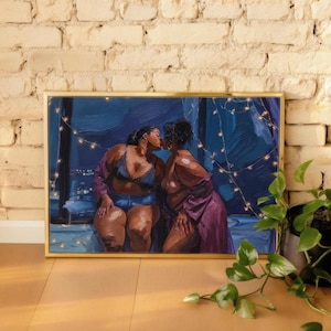 a framed painting of two women in intimate poses, with one woman appearing to kiss the other. The painting is set against a backdrop of a brick wall, and there is a potted plant to the right of the frame.