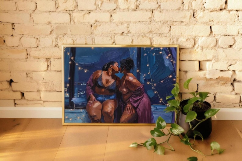 a framed painting of two women in intimate poses, with one woman appearing to kiss the other. The painting is set against a backdrop of a brick wall, and there is a potted plant to the right of the frame.