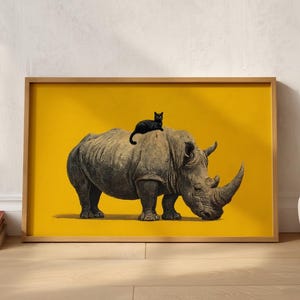May include: A framed horizontal wall art print featuring a detailed illustration of a grey rhinoceros standing in profile with a small black cat resting on its back, set against a solid, vibrant mustard yellow background within a light wood frame.