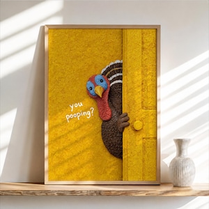 May include: A framed wall art print featuring a textured yellow background and a yellow door. A brown turkey with a red wattle and blue face peeks from behind the door. The white text on the yellow wall reads, you pooping? The art is rectangular.
