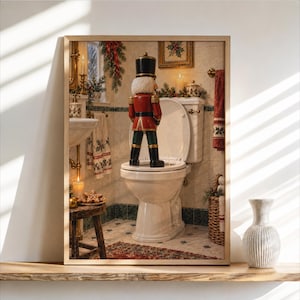 Può includere: Una stampa artistica incorniciata raffigurante una statuetta di schiaccianoci in piedi sulla tavoletta di un water bianco in un bagno decorato per le feste. Lo schiaccianoci indossa una giacca rossa, un cappello nero e pantaloni scuri con decorazioni.