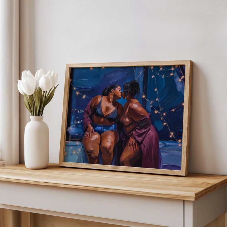 May include: A framed art print depicting two individuals kissing in a dimly lit room with string lights. One person wears a dark lace bralette and denim shorts, while the other wears a purple robe. The scene is set against a deep blue background.