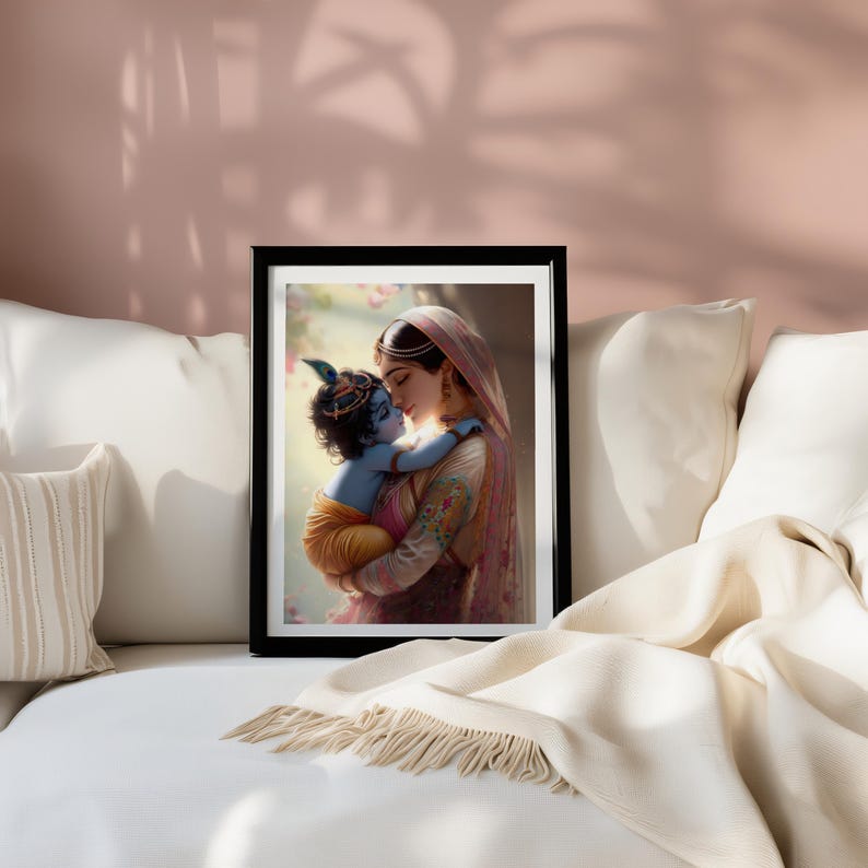 A framed painting of a woman holding a child is displayed on a white couch, with a beige blanket and pillows in the foreground.