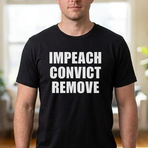Puede incluir: Una camiseta negra de manga corta con el texto blanco IMPEACH CONVICT REMOVE impreso en una fuente negrita y sin remates en el pecho. La prenda tiene cuello redondo y un corte estándar, combinada con pantalones vaqueros azules.