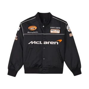 Op de afbeelding: Zwarte McLaren Formule 1 racejack met witte accenten en patches. Voorzien van het McLaren-logo in wit en oranje, en de tekst "There is no finish line." Inclusief een knoopsluiting en twee zakken.