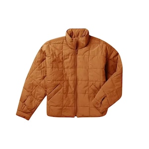 Könnte beinhalten: Eine gesteppte, rostfarbene Jacke mit hohem Kragen und durchgehendem Reißverschluss. Die Jacke hat ein rautenförmiges Design und zwei Vordertaschen. Die Ärmel haben geknöpfte Manschetten. Dieses Oberbekleidungsstück ist für kühleres Wetter geeignet.
