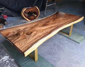 Tavolo da pranzo artigianale in acacia dorata con bordo naturale e gambe in acciaio personalizzate.